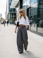 Pleated wide-leg trousers in pinstripe grey, worn by a model on the street